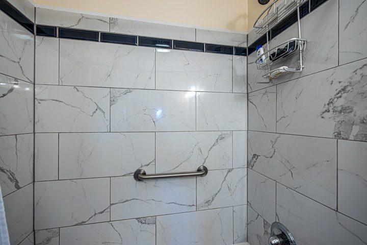 Marble-look tiled shower with a grab bar