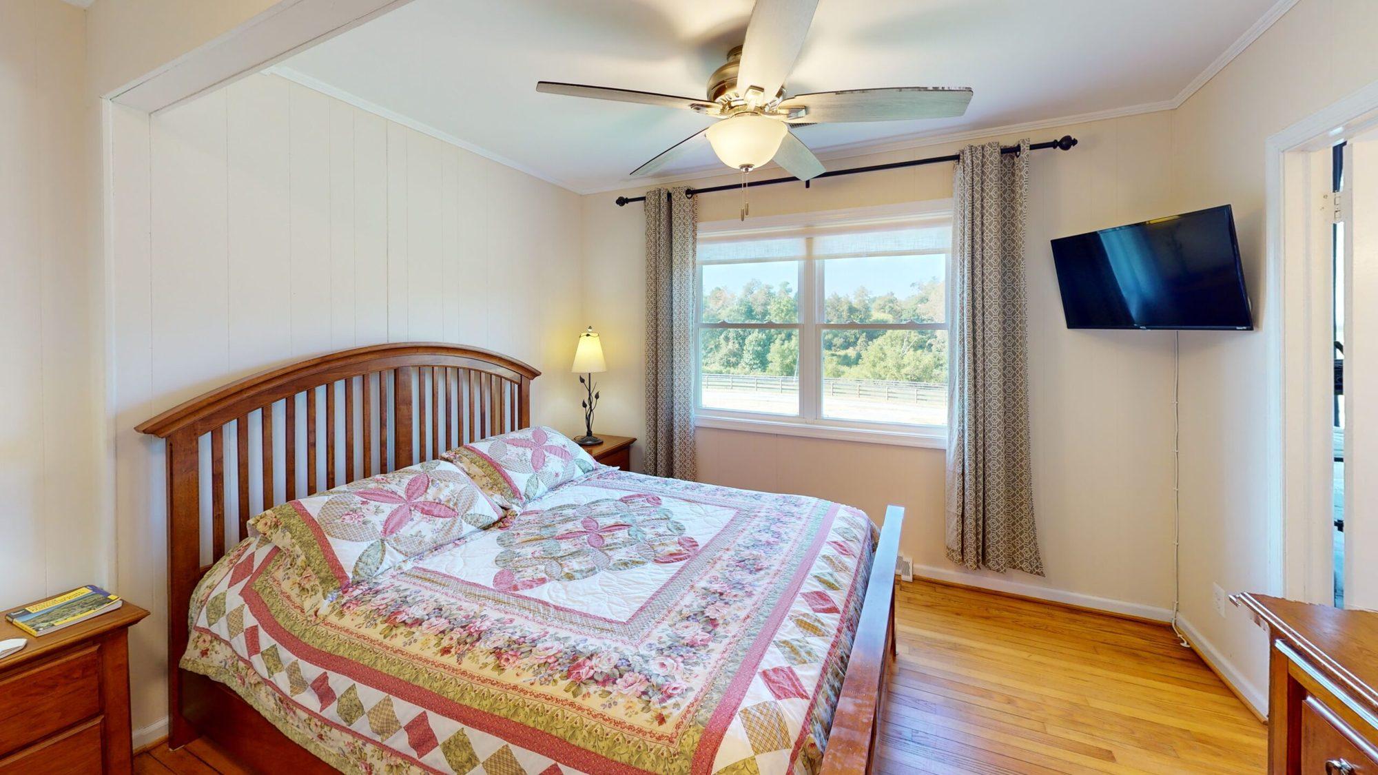 Bedroom with a quilted bed and a wall-mounted TV