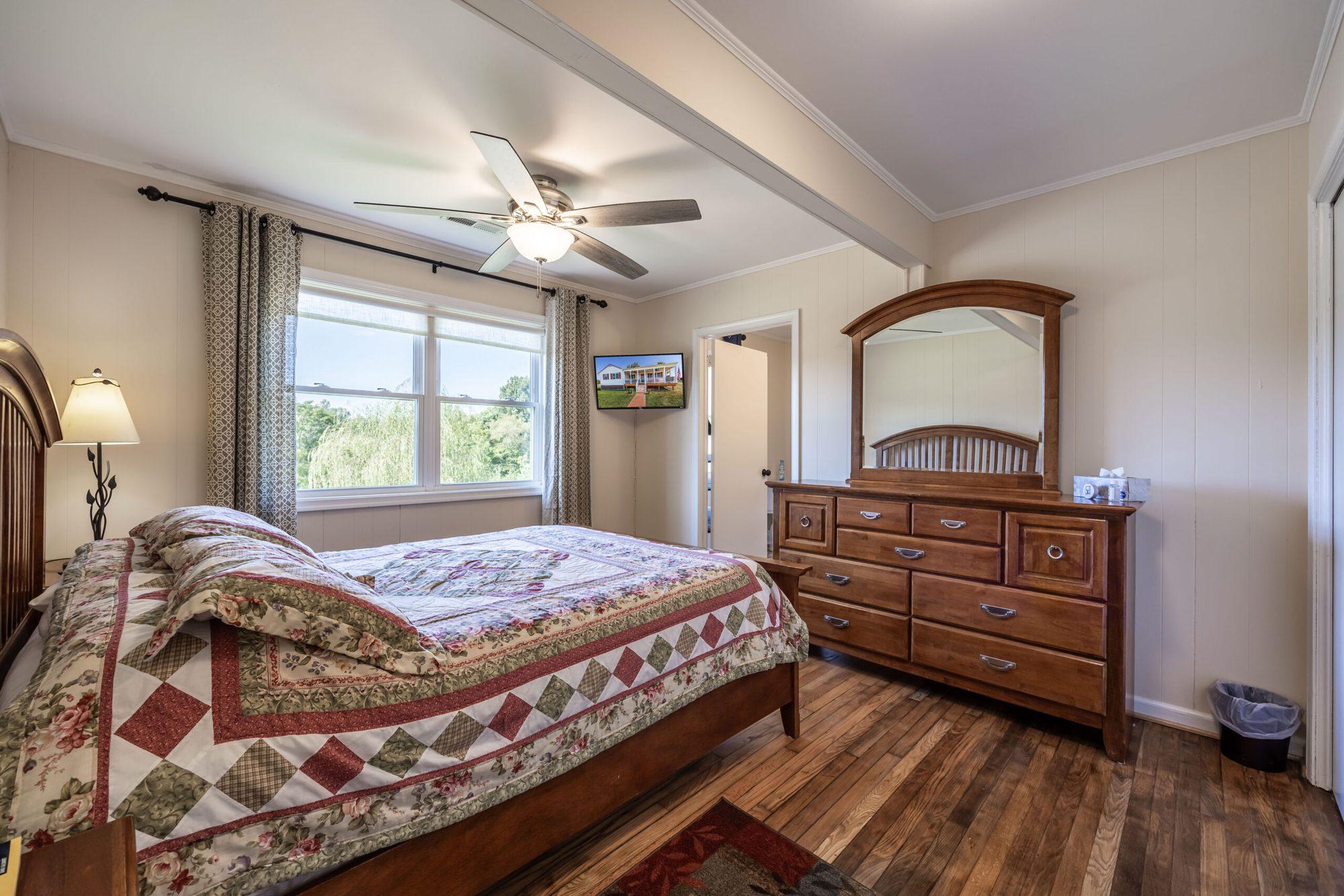 Bedroom with a quilted bed, dresser and mirror