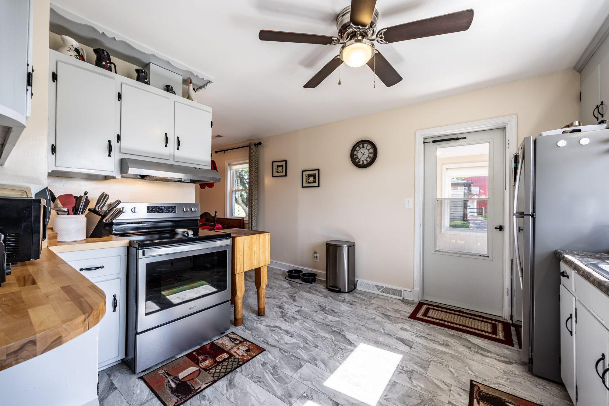 Kitchen with white cabinets, a butcher-block island and a stainless stove
