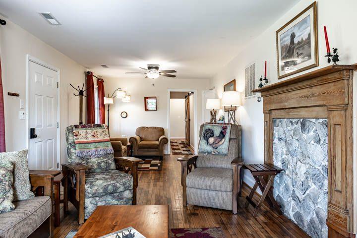 Living room seating beside a stone and wood fireplace