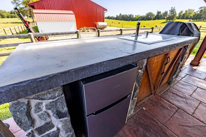 Outdoor kitchen with a stone counter, sink and mini fridge