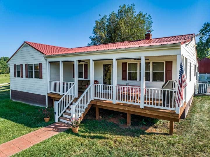The Whindale Ranch farmhouse with a covered front porch and red metal roof