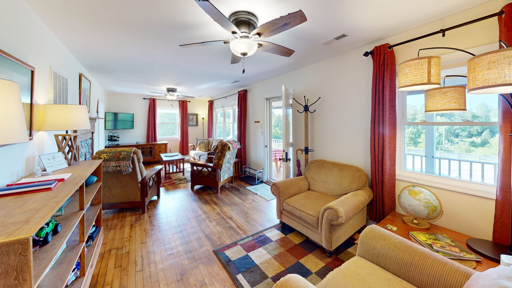 Living room with armchairs, bookshelves and tall windows